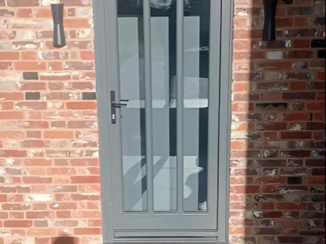 Grey painted glazed door in a brick wall